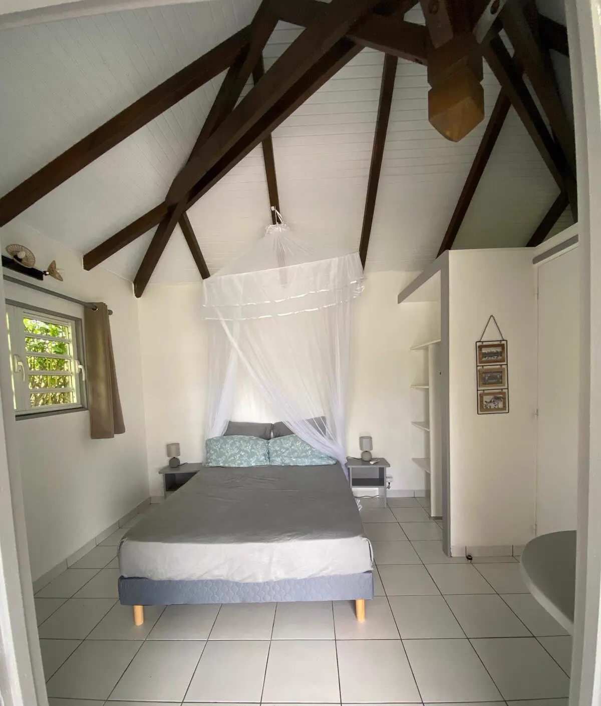 La chambre du bungalow sous charpente apparente, lit double équipé d'une moustiquaire