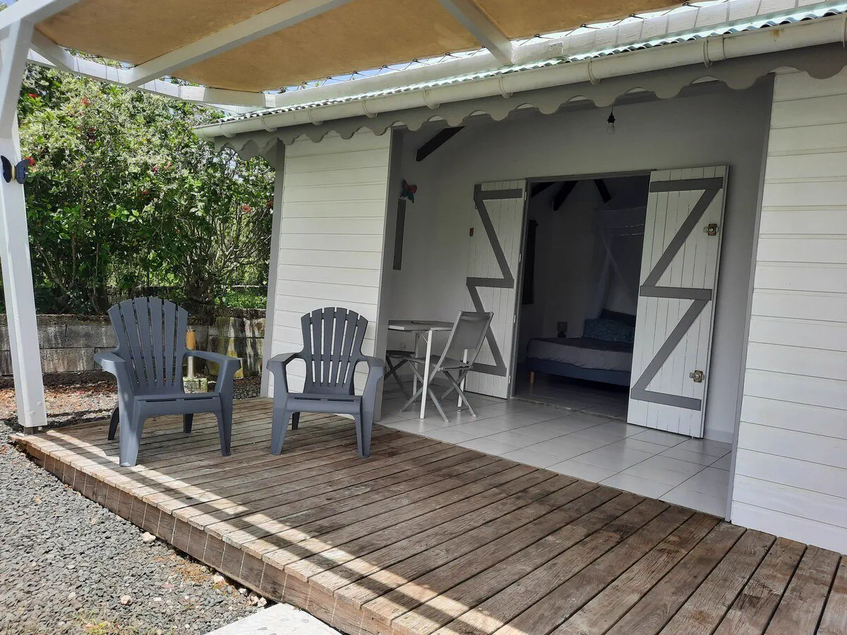 La terrasse couverte en bois du bungalow, avec deux fauteuils de jardin et une table