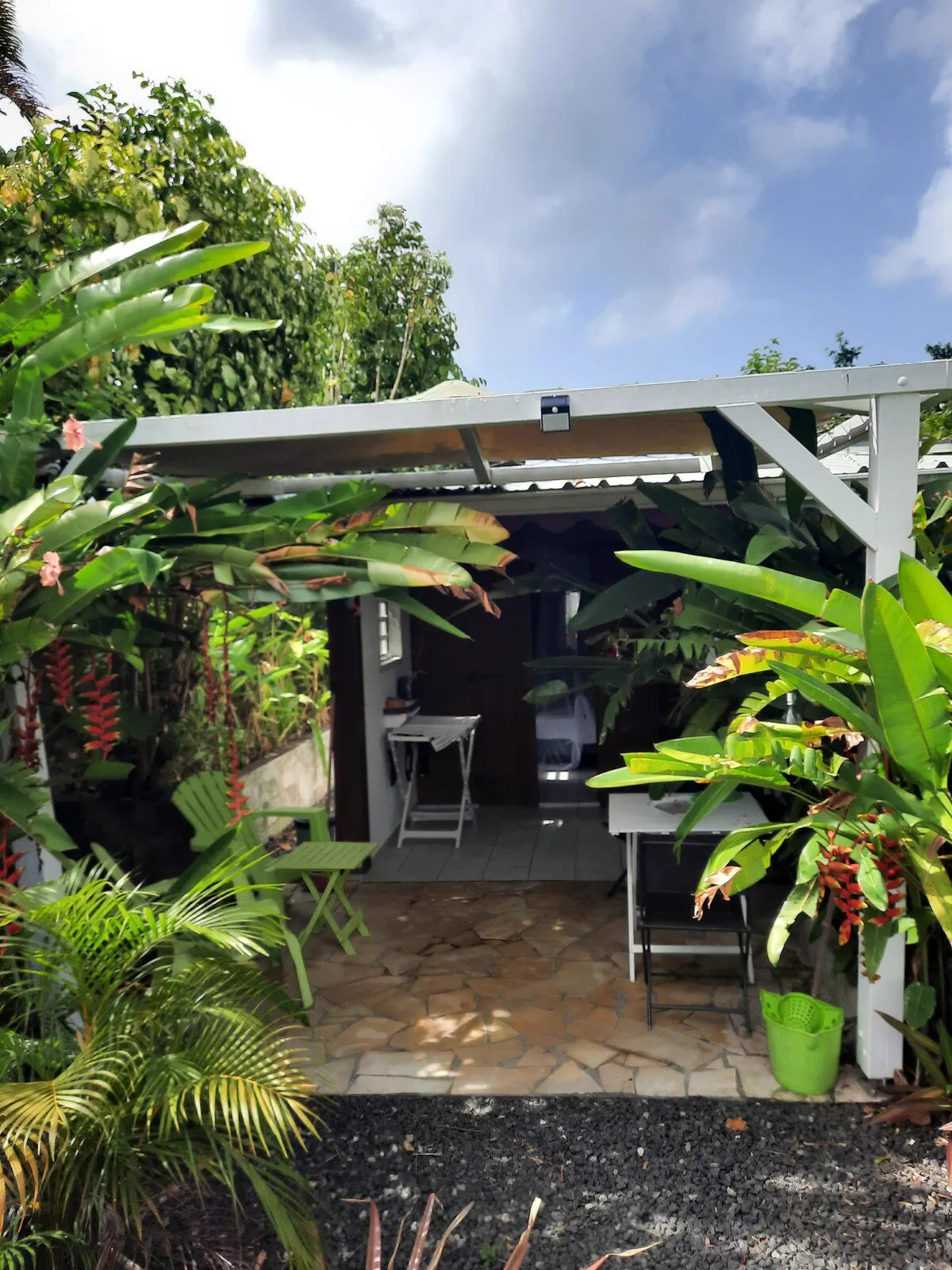 L'entrée du studio sous sa terrasse couverte, encadrée de plantes tropicales