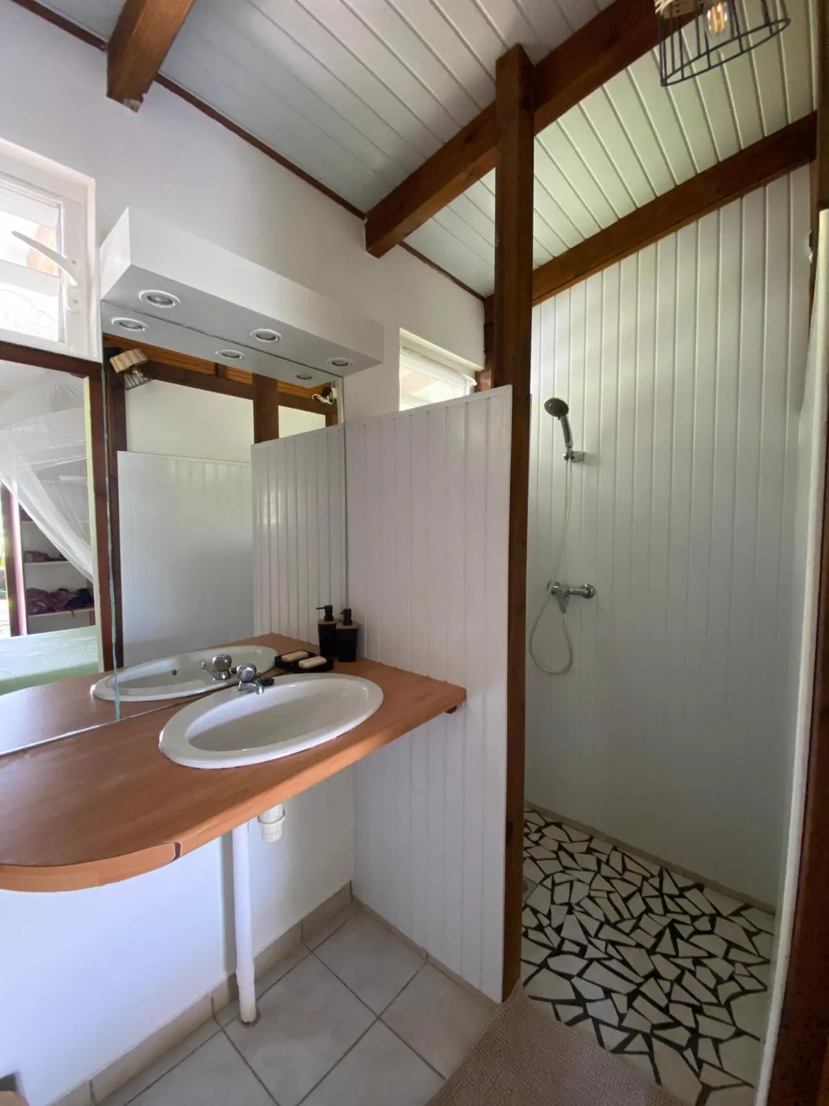 La salle d'eau du studio : plan en bois avec lavabo et douche à l'italienne au sol de galets
