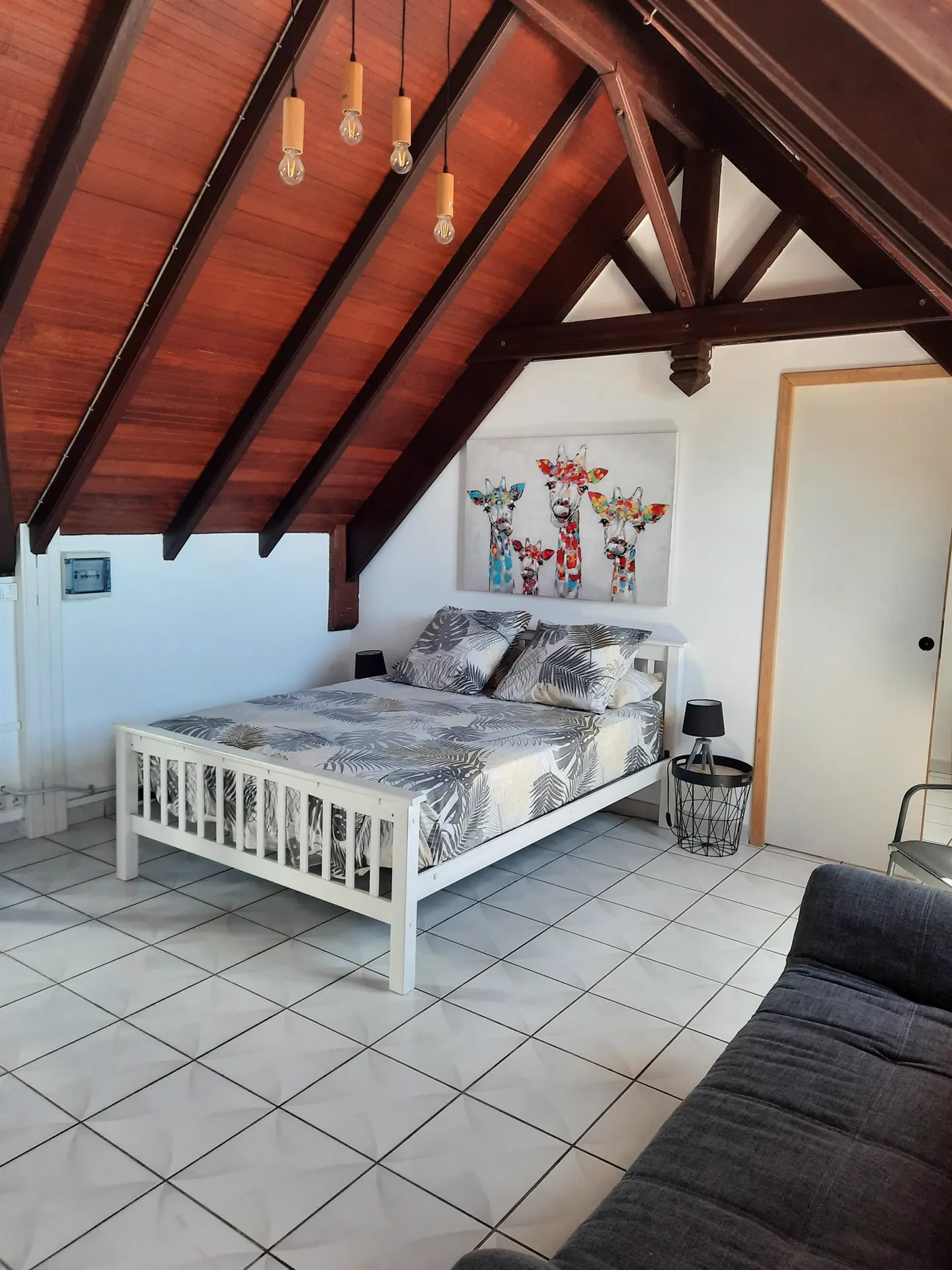 La chambre de O'Morne sous charpente en bois, lit double et suspensions