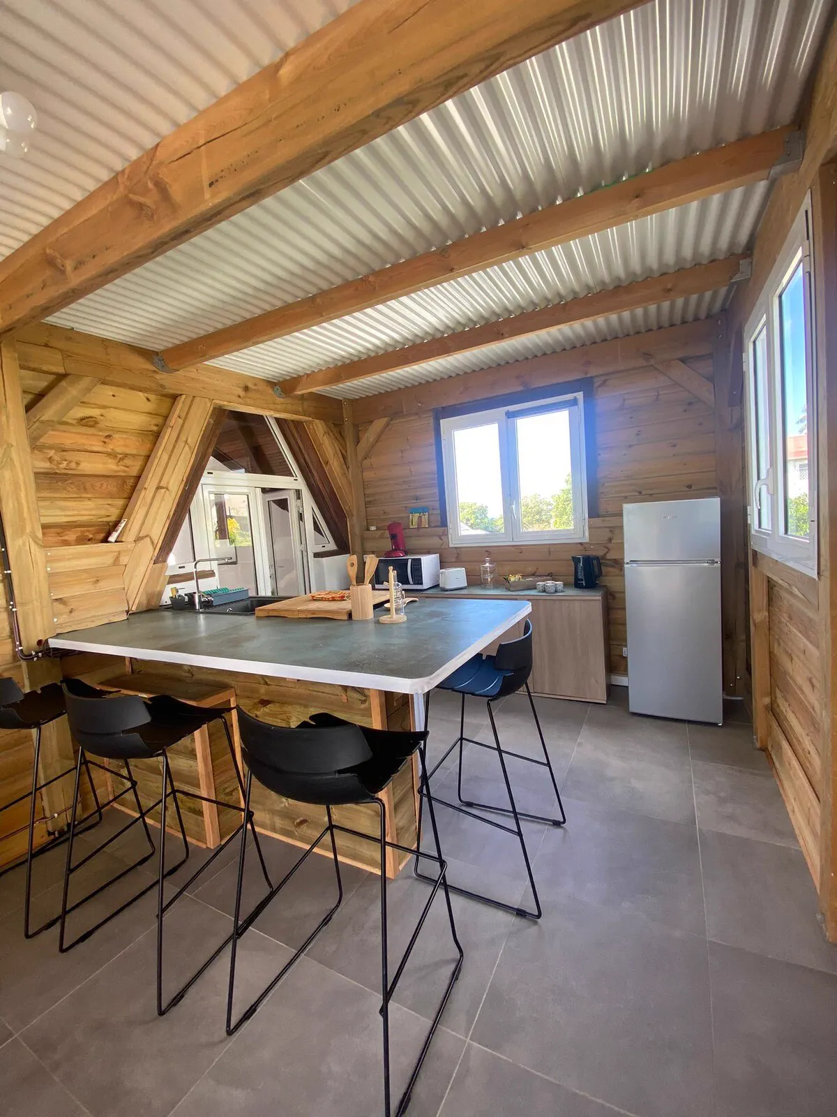 L'espace repas de O'Morne : table haute et quatre tabourets, sous charpente en bois